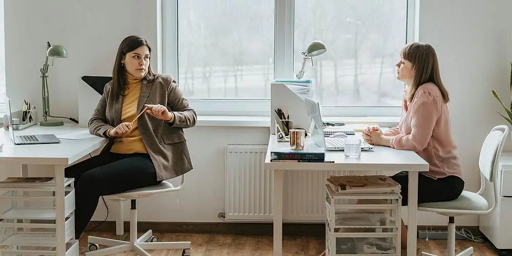 Zwei Personen im Büro unterhalten sich Zwei Personen im Büro unterhalten sich