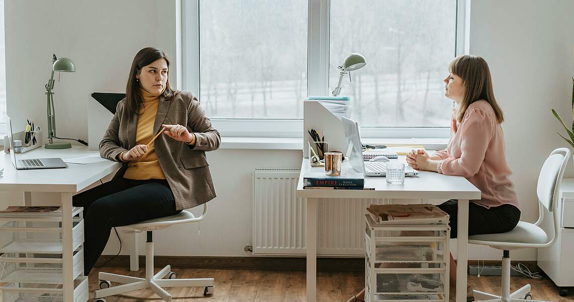 Zwei Personen im Büro unterhalten sich Zwei Personen im Büro unterhalten sich